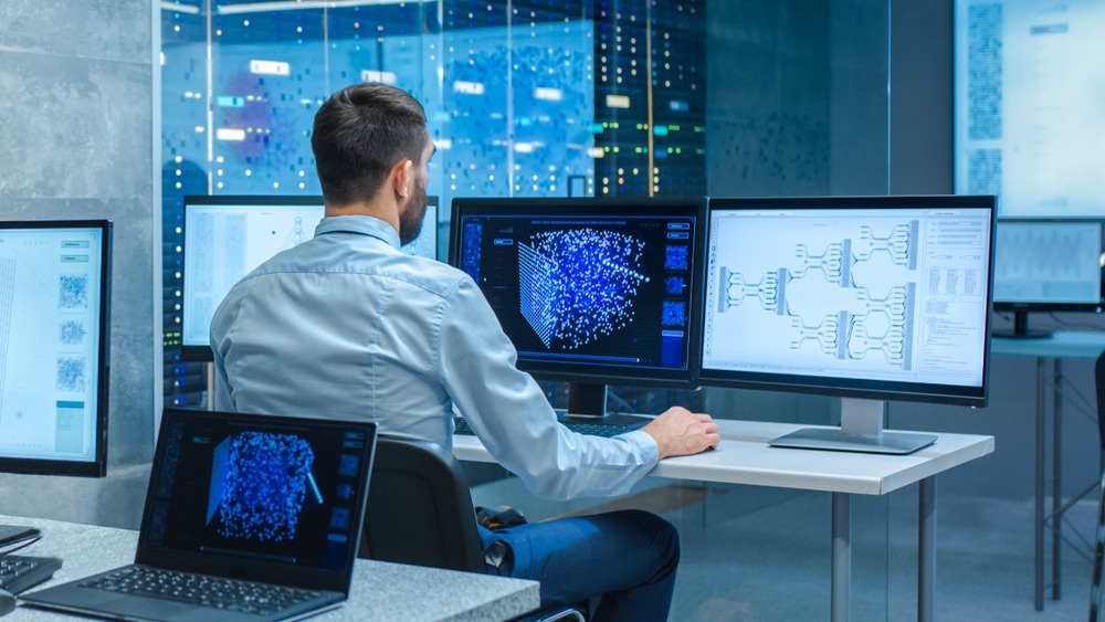 Man monitoring data on multiple computer screens
