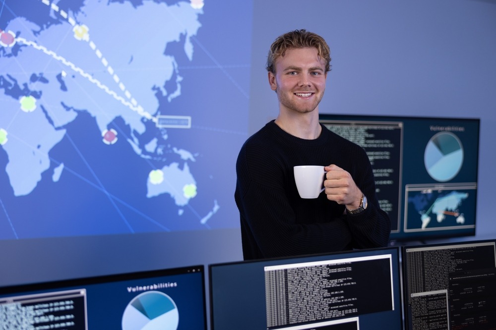 Smiling cybersecurity analyst with coffee